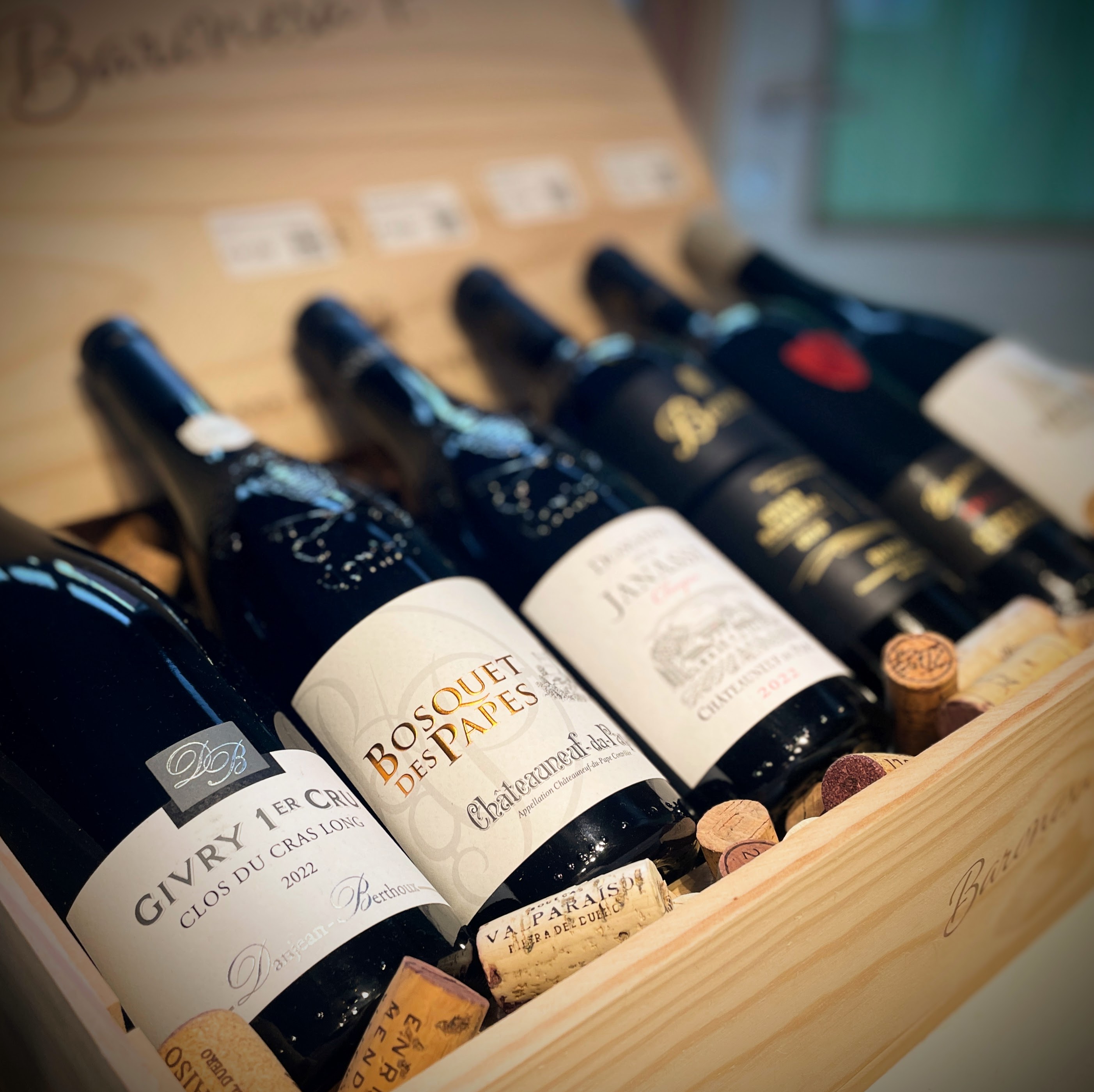 Selectie karaktervolle wijnflessen in een houten kist voor de popup cadeaushop van De Proeverij